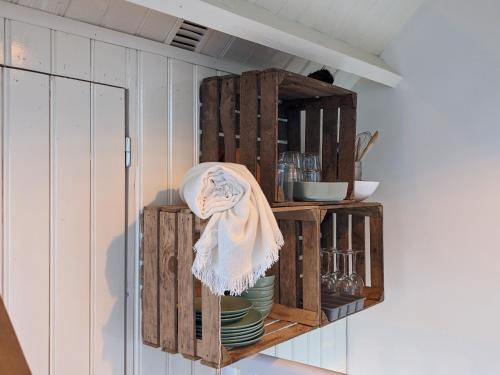 a kitchen with wooden cabinets and plates on a shelf at CRASH'NSTAY - Weidezicht in Sprang-Capelle