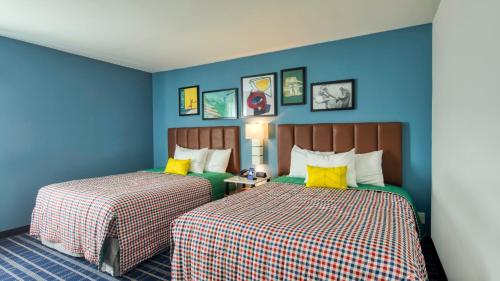 2 Betten in einem Zimmer mit blauen Wänden und gelben Kissen in der Unterkunft Uptown Suites Extended Stay Charlotte NC - Concord in Concord