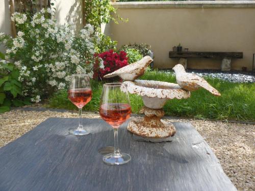 two glasses of wine sitting on a wooden table at Chambres d'hôtes Rue du Poids in Bourgueil