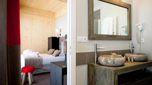 a bathroom with a sink and a bedroom with a bed at L'Aiguille Grive Chalets Hotel in Arc 1800