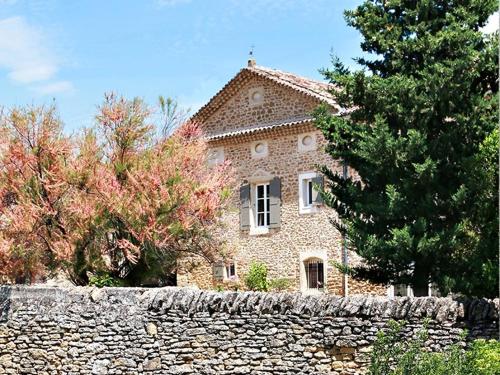 una gran casa de piedra detrás de una pared de piedra en Le Clos de la Tuilière, en Grignan