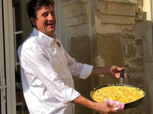 a chef holding a pan with a pizza at Le Clos de la Tuilière in Grignan