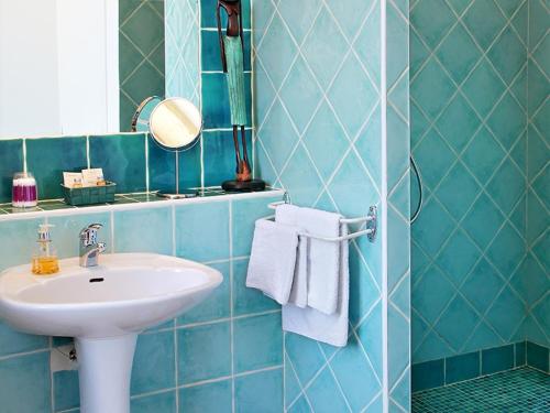 a blue tiled bathroom with a sink and a mirror at Le Clos de la Tuilière in Grignan