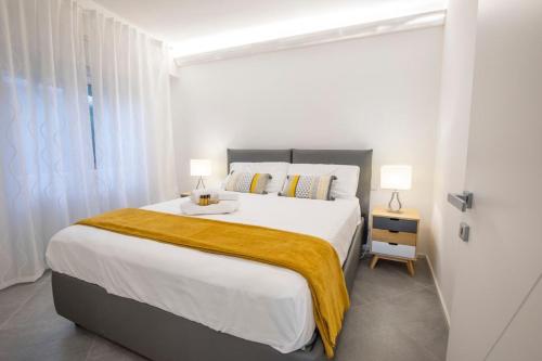 a white bedroom with a large bed with a yellow blanket at Camy’s Sunset Bay-Attico vista mare in Bergeggi