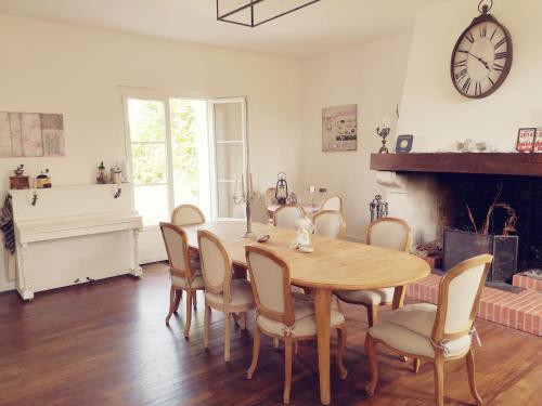 ein Esszimmer mit einem Tisch, Stühlen und einer Uhr in der Unterkunft Le Petit Domaine de Colayrac in Colayrac-Saint-Cirq