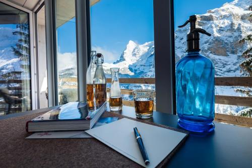 a desk with a bottle and a pen and a book at Hotel Edelweiss Superior in Mürren