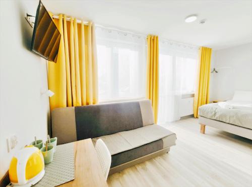 a bedroom with a couch and a bed and yellow curtains at Zefiro Ogrody in Gdańsk