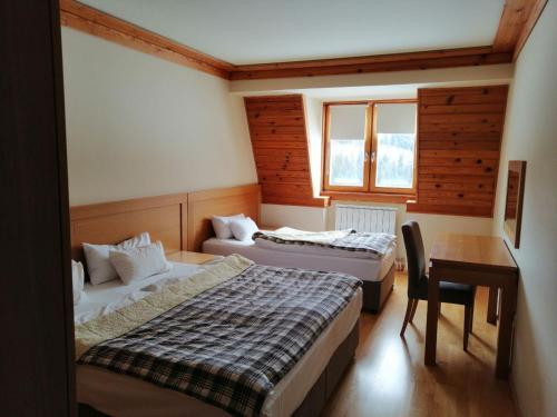 a room with two beds and a table and a desk at Apartman 205 Aparthotel Vučko in Jahorina