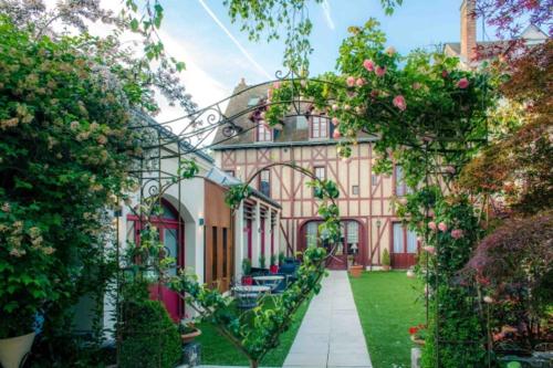 une grande maison avec un jardin orné de roses dans l'établissement Hotel Spa - Au Charme Rabelaisien, à Amboise