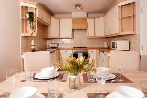a kitchen with a table with plates and glasses at 3 Bed Townhouse Stafford in Stafford