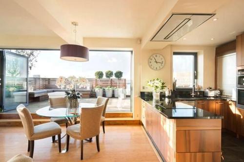 2 Bed Luxury apartment in Bayswater - amazing terrace views from 7th floor في لندن: مطبخ مع طاولة وكراسي وساعة