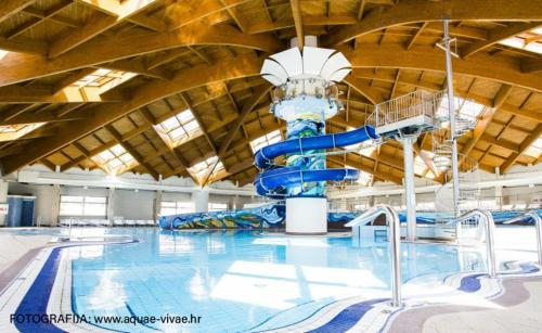 a large indoor swimming pool with a water slide at Apartmani Strsoglavec in Krapinske Toplice