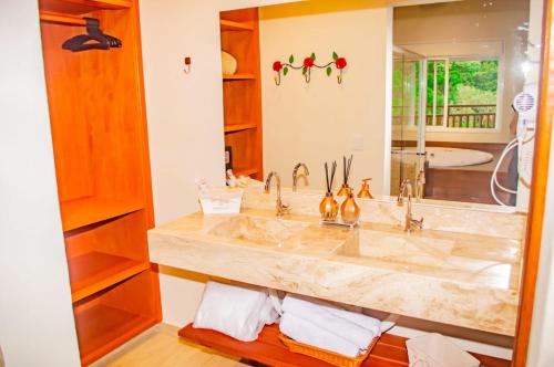 a bathroom with a sink and a large mirror at Chalés Estrela da Mantiqueira in Monte Verde