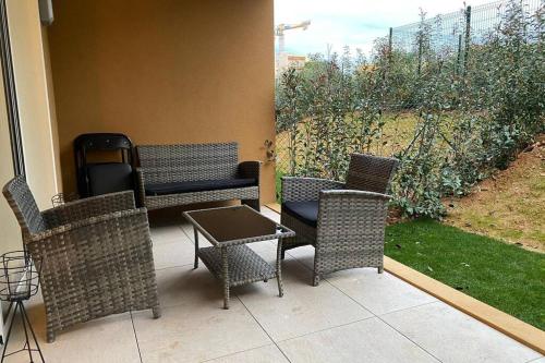 a patio with wicker chairs and a table and a fence at Deux pieces Moderne et Chaleureux in Saint-Laurent-du-Var