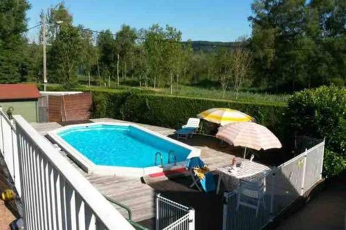 - une piscine avec un parasol et des chaises dans l'établissement Maison/Gîte familial dans le Jura à 200m du lac avec piscine privée, à Marigny