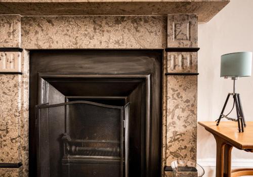 a black fireplace in a living room with a lamp at Scott's View in North Berwick