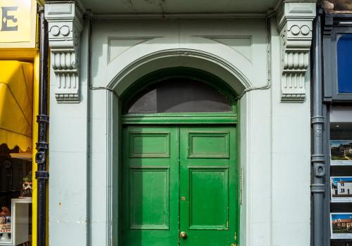 a green door in a white building with an arch at Scott's View in North Berwick
