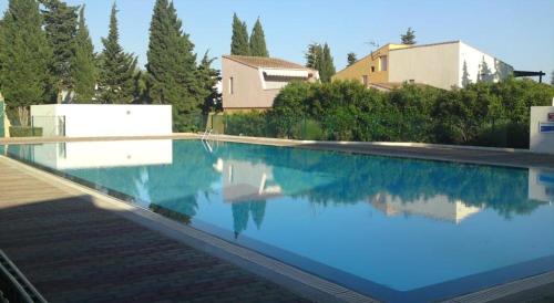 a swimming pool with blue water in front of a house at Hotel Tennis International in Cap d'Agde