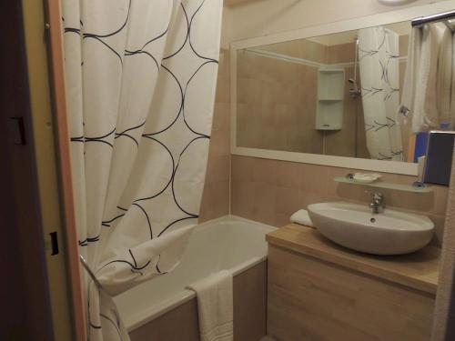 y baño con lavabo, bañera y espejo. en Hotel Tennis International, en Cap d'Agde