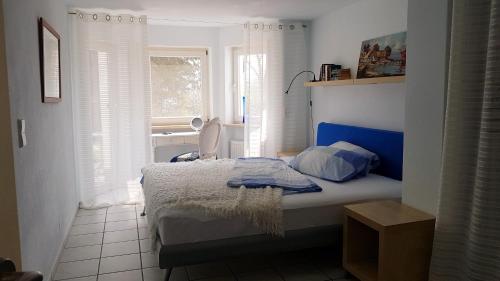 Schlafzimmer mit einem Bett mit blauem Kopfteil und einem Fenster in der Unterkunft Ferienwohnung Granzow in Gaienhofen