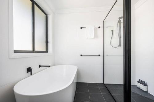 a white bathroom with a tub and a glass shower at 'Campanile House' The Ultimate Mudgee Adventure in Mudgee