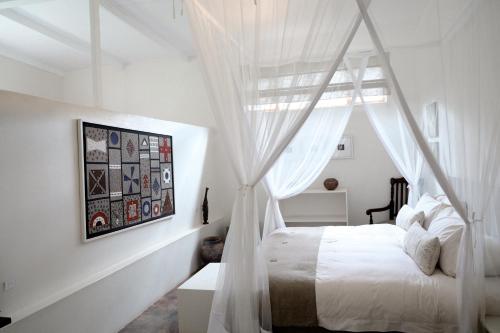 a bedroom with a canopy bed with white curtains at Madi a Thavha Mountain Lodge in Louis Trichardt
