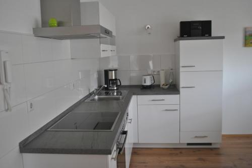 a white kitchen with white cabinets and a sink at Ferienhaus Rauwolf in Roschbach