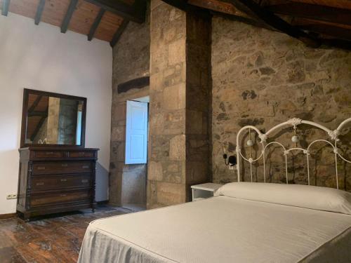 1 dormitorio con cama y pared de piedra en Casa Goris, en Merza