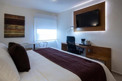 a bedroom with a bed and a desk and a television at Mision Express Merida Altabrisa in Mérida