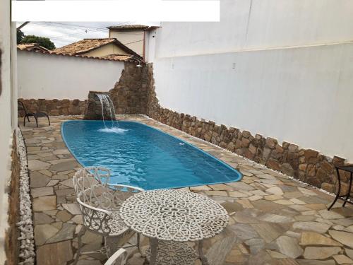 una piscina con una mesa y una fuente en Tiradentes Pousada Ramalhete, en Tiradentes
