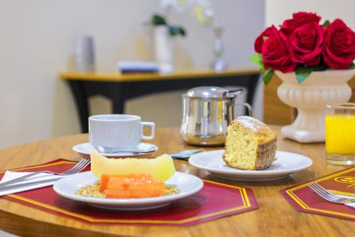 una mesa con dos platos de comida y un trozo de tarta en Hotel Dan Inn Sorocaba, en Sorocaba