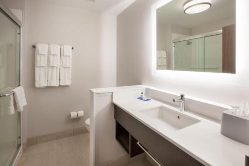 Baño blanco con lavabo y espejo en Holiday Inn Express & Suites - Morehead City, an IHG Hotel en Morehead City