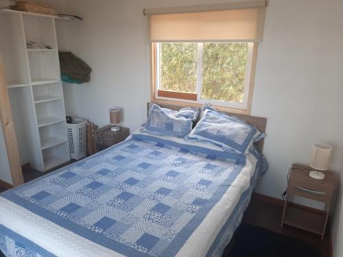 um quarto com uma cama azul e branca e uma janela em CASA BLANCA SPA em Puchuncaví