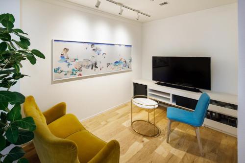 a living room with a tv and a couch and chairs at The Screen in Kyoto