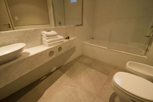 a bathroom with a sink and a toilet and a tub at Triplex con terraza única a 50 mts del mar in Carilo