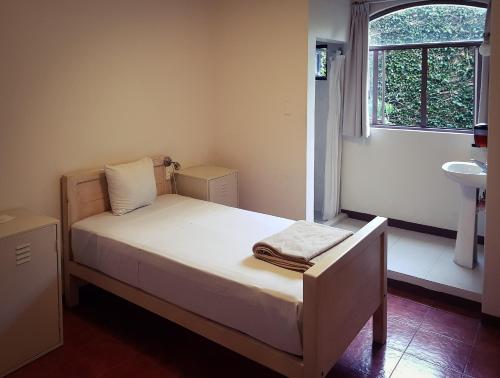 um pequeno quarto com uma cama e um lavatório em Hostal de Las Américas em Oaxaca de Juárez