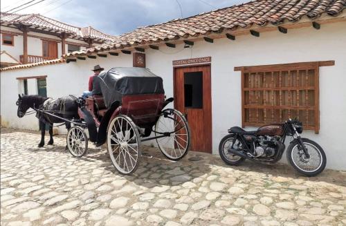 une calèche tirée par des chevaux garée à côté d'une moto dans l'établissement Hostel Once Once, à Villa de Leyva