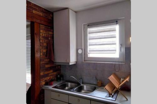 une cuisine avec un évier et une fenêtre dans l'établissement Petite Maison pleine de charme au Tréport....., au Tréport