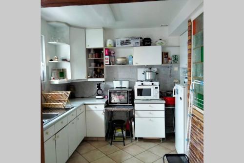 une cuisine avec des armoires blanches et un four à plaques de cuisson dans l'établissement Petite Maison pleine de charme au Tréport....., au Tréport