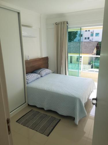 een slaapkamer met een bed en een groot raam bij Apto Queen D'Arte Bombinhas in Bombinhas