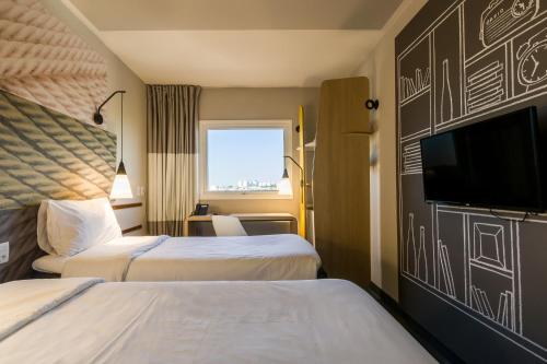 um quarto de hotel com duas camas e uma televisão de ecrã plano em Ibis Americana em Americana