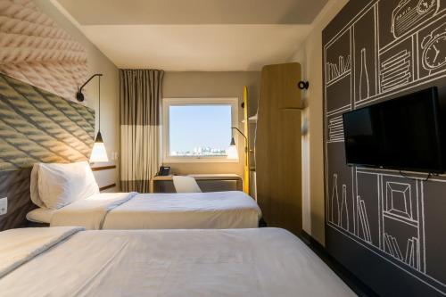 a hotel room with two beds and a flat screen tv at Ibis Americana in Americana