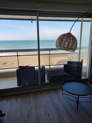 ブローニュ・シュル・メールにあるLa Pause Du Week Endのビーチの景色を望む客室で、テーブルと椅子が備わります。