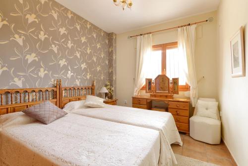 a bedroom with two beds and a desk and a window at Villa Sonada Busot private pool in Busot