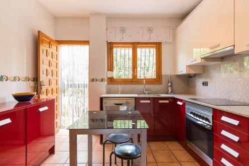 a kitchen with red cabinets and a glass table at Villa Sonada Busot private pool in Busot