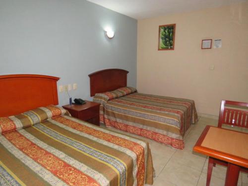 比亞埃爾莫薩的住宿－Hotel San Juan Centro，酒店客房设有两张床和一张桌子。