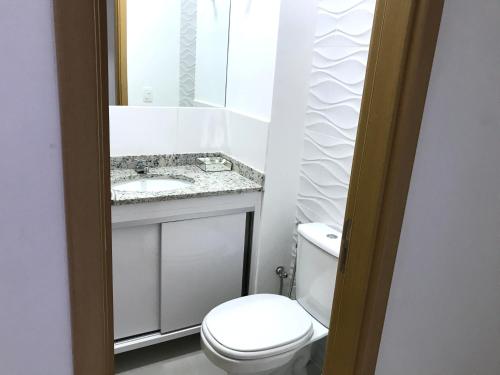 a white bathroom with a toilet and a sink at Apartamento Resort em Praia grande - Ubatuba in Ubatuba