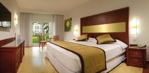 a bedroom with a large bed and a desk at Riu Jalisco - All Inclusive in Nuevo Vallarta