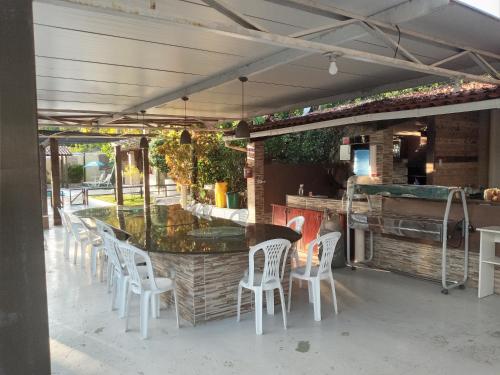 a patio with white chairs and a bar with a counter at Pousada Santa Tereza in Itapissuma