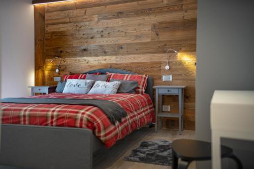 1 dormitorio con 1 cama con pared de madera en Maison Altea, en Courmayeur